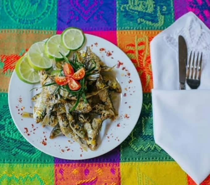 Topotes fritos servidos en plato blanco con limón y tomate